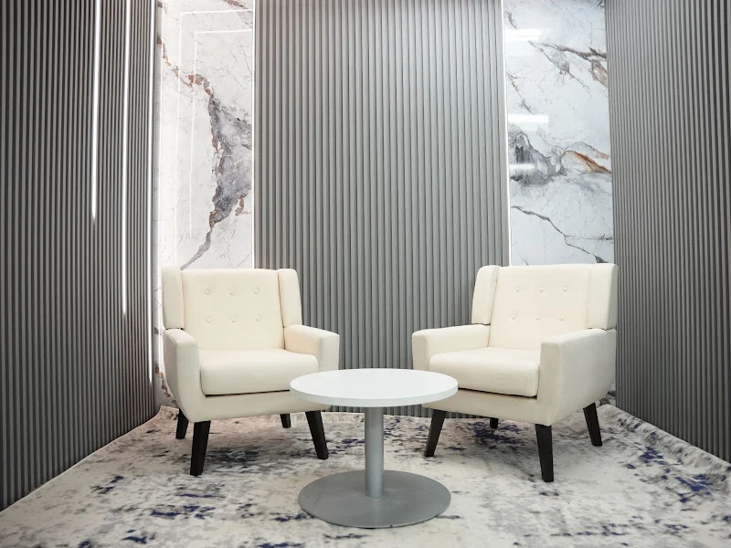 Grey-panel podcast studio with two cream armchairs and a round table