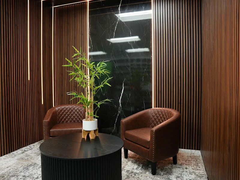 Wood-panel podcast studio with two brown leather chairs and a round table